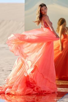 a woman in an orange dress standing on the beach