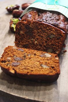 a loaf of bread sitting on top of a wooden cutting board next to some raisins