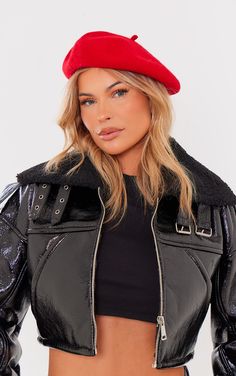 a woman wearing a black leather jacket and red beret with zippers on the sides