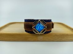 a blue and brown bracelet sitting on top of a wooden board