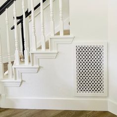 a cat is sitting on the floor next to some stairs and a heat grate