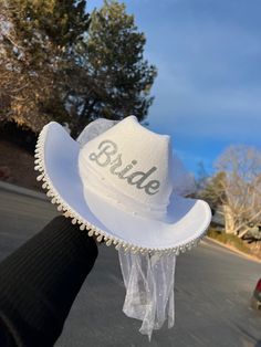 a white hat with the word bride on it is held up by someone's hand