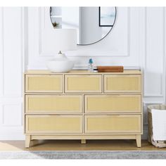 a dresser with a mirror above it and a basket on the floor next to it