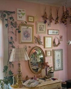 a room with pink walls and lots of pictures on the wall, including a mirror