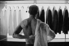 a man standing in front of a rack of shirts