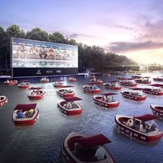 a group of boats floating on top of a river next to a large screen tv