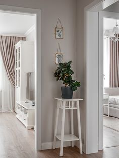 a living room with a potted plant next to a white table and couches