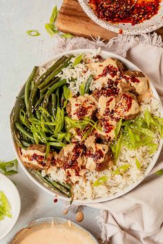 a white bowl filled with rice and green beans next to another bowl full of food