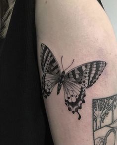 a black and white butterfly tattoo on the arm