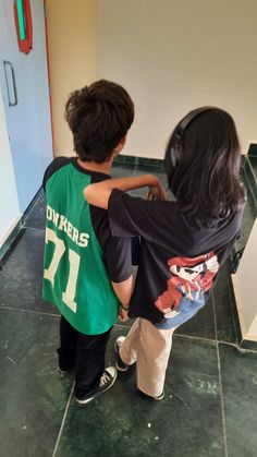 two young boys standing next to each other in front of a bathroom mirror with their arms around each other