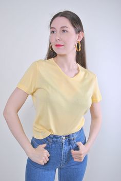 Indulge in the retro charm of our 90s Yellow Pullover Top, a vintage gem from TARASCOMMON.ETSY.COM's collection of unique clothing from the 20th century. Size: M Sleeve: 1.57 inches (armpit to end of sleeve) Width: 17.32 inches Length: 19.68 inches This vintage pullover features a minimalist design with a flattering v-neck, perfect for adding a pop of color to your wardrobe. Whether you're aiming for a retro look or a casual ensemble, this top is versatile and timeless. Crafted from comfortable Vintage V-neck T-shirt For Spring, Retro V-neck T-shirt For Summer, Retro V-neck T-shirt For Spring, Vintage Cotton V-neck Top, Vintage Cotton V-neck T-shirt, Retro Cotton V-neck Tops, Yellow Minimalist, Retro Yellow, Retro Minimalist