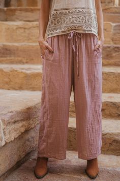 a woman standing in front of some steps wearing pink pants and a white tank top