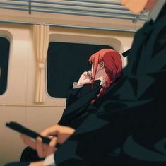 two people sitting on a train looking at their phones