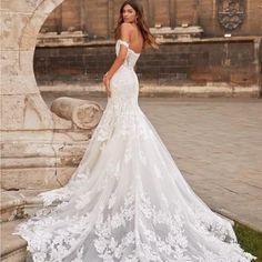 a woman in a white wedding dress posing for the camera with her back to the camera