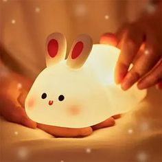 a person is holding a small light with bunny ears on it's face and hands