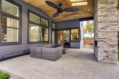 an outdoor living area with two wicker chairs and a ceiling fan