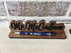 a wooden pen holder with the word mr and mrs california on it, next to a blue ballpoint pen