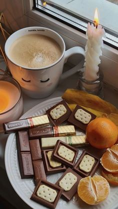 a plate with crackers, orange slices and marshmallows next to a cup of coffee