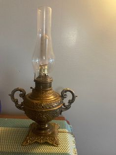 an old fashioned lamp sitting on top of a table next to a blue glass vase