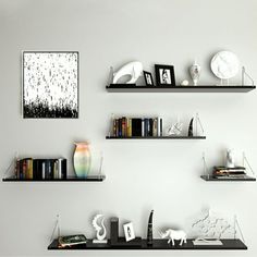 three black shelves on the wall with books and other items in them, along with an animal figurine