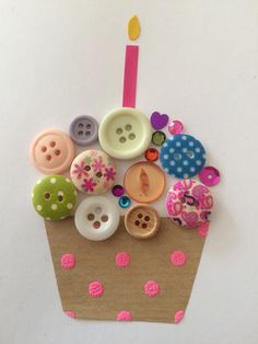 a cupcake decorated with buttons and a candle