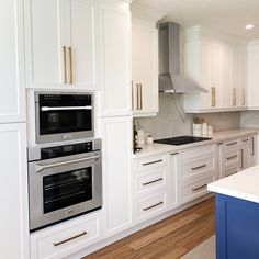 a kitchen with white cabinets and stainless steel ovens in the center, along with an island