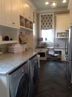 a washer and dryer in a small room with white cabinetry, wood flooring and open shelving