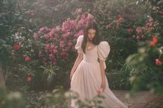 a woman in a white dress walking through flowers