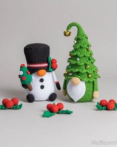 two crocheted snowmen next to a small christmas tree and one is wearing a top hat