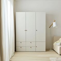 a bedroom with white furniture and curtains on the window sill, next to a bed