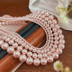 a bunch of pearls are on top of a wooden book with flowers in the background