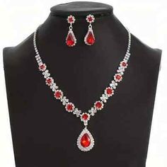 a necklace and earring set with red stones on a black mannequins