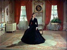 a woman in a long black dress is walking through a room