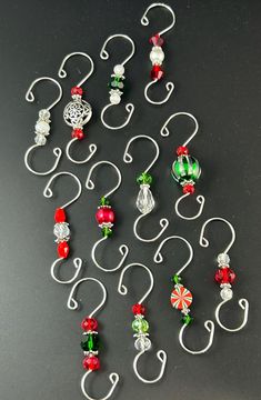 several christmas ornaments are hanging from hooks on a black surface with white and red trimmings