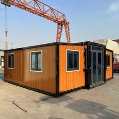 a crane is standing on top of a small building that's being built into the ground