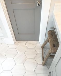 a wooden chair sitting in front of a door on top of a tiled floor next to a doorway