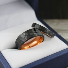 two wedding rings are in a box on the table, one is gold and the other is black