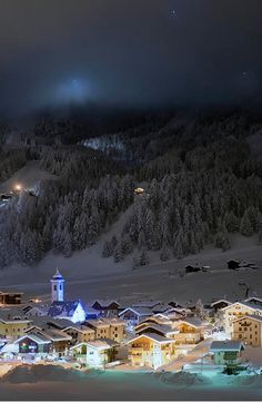 a town is lit up at night in the snow