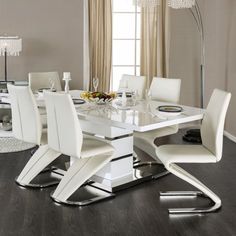 a dining room table with white chairs and a chandelier