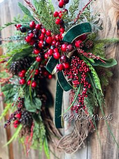 a christmas wreath hanging on the side of a wooden door with berries and evergreens