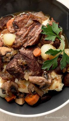 a bowl filled with meat, potatoes and carrots