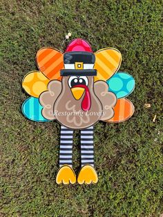 a turkey shaped kite on the ground with grass in the foreground and an image of a turkey wearing a hat