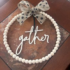 a white beaded bracelet with the word gather on it and a bow hanging from the front