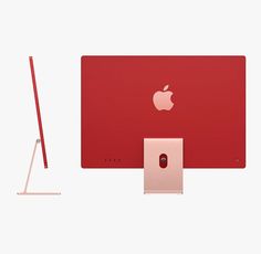 an apple computer with a red screen and keyboard on it's side, next to a metal stand