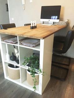 a desk with a computer on top of it and some plants in front of it