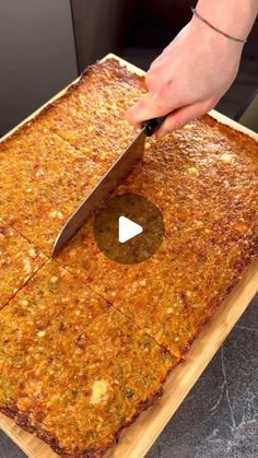 a person cutting up food on top of a wooden cutting board with a large knife