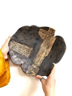 a person holding up a metal plate with a cross on it's face and yellow jacket