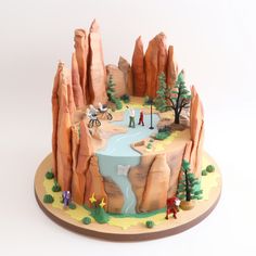 a cake that is shaped like a mountain with people riding bikes on the top and around it