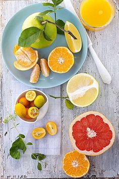 various citrus fruits are arranged on a wooden table with oranges, lemons and grapefruit