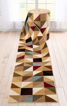 a multicolored area rug with an abstract design on the floor in front of a window